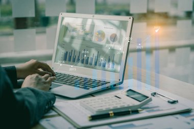 İş adamı dizüstü bilgisayarla iş arkadaşlarına mesajlar yazıyor ve toplantıyı sonlandırmak için mali bilgileri belgeliyordu. Resimleri kapat