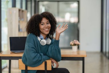 Oturma odasında dizüstü bilgisayarla çalışıp internetten bilgisayar kullanarak öğrenen Afrikalı genç bir üniversite öğrencisi. Gülümseyen kız Webinar ya da uzaktan eğitim dersi izliyor.