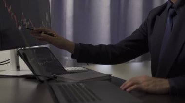 Genç Asyalı borsacı, bilgisayarın geniş ekranındaki hisse senedi diyagramına bakan genç bir iş adamının kafasının arkasını inceliyor..