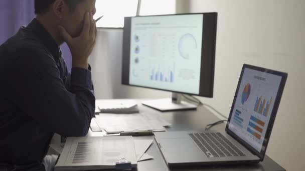 若いビジネスマンは 彼のオフィスで働くプロジェクト分析に焦点を当てています 深夜まで コンピュータ画面で市場 財務会計コンセプト — ストック動画