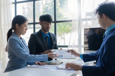 Bir grup başarılı genç iş adamı toplantılarda finansal raporlar sunuyor ve iş stratejilerini analiz etmek ve planlamak için beyin fırtınası fikirleri sunuyorlar..