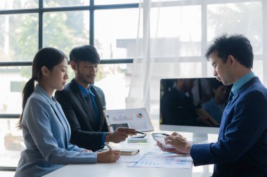 Bir grup başarılı genç iş adamı toplantılarda finansal raporlar sunuyor ve iş stratejilerini analiz etmek ve planlamak için beyin fırtınası fikirleri sunuyorlar..