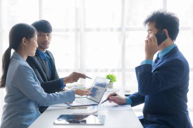 Bir grup başarılı genç iş adamı toplantılarda finansal raporlar sunuyor ve iş stratejilerini analiz etmek ve planlamak için beyin fırtınası fikirleri sunuyorlar..