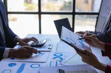Fon yöneticisi ekibi, konferans odasındaki mali durumu analiz etmek ve tartışmak üzere dijital tablet iş danışmanlarıyla görüşerek borsa analizini ele alır ve tartışır.
