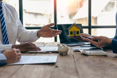 Emlakçı ve alıcı ev kredisi toplantısı sırasında kontrat imzaladılar. Başarılı yeni ev sahipleri için emlak satış sözleşmeleri ve ücretsiz sigorta.