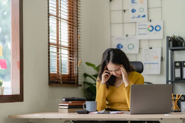 Asian businesswoman having eye strain and feeling sleepy at desk in office working with laptop or notebook The concept of hard worker and burnout syndrome.