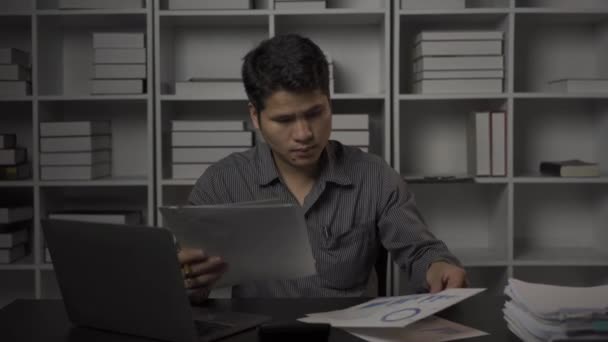 持财务文件和台式计算机工作到深夜的亚洲男性商人 加班的年轻人 领薪者概念4K — 图库视频影像