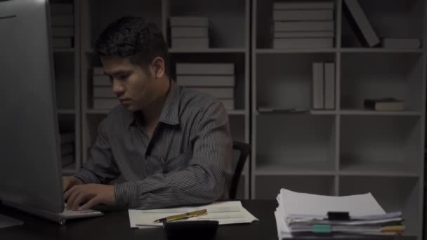 持财务文件和台式计算机工作到深夜的亚洲男性商人 加班的年轻人 领薪者概念4K — 图库视频影像