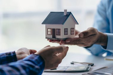 Emlakçı ev satın alma anlaşmasının şartlarını tartışıyor ve müşteriden sözleşmeyi imzalamasını ve evi teslim etmesini istiyor..