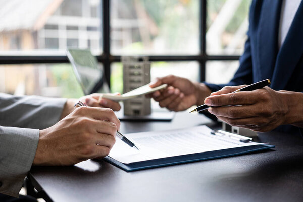 Агент по недвижимости обсуждает условия договора купли-продажи жилья и просит клиента подписать документы для заключения контракта и сдачи дома.