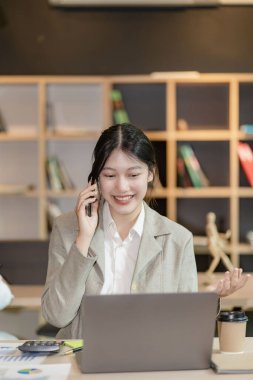 Asyalı bir kadın bilgisayarlı, Asyalı bir iş kadını muhasebeci ile ofisinde oturuyor. dikey resim