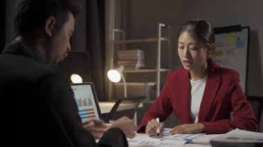 Genç Asyalı işadamı, kadın ve erkek dizüstü bilgisayarlar ve finansal belgelerle birlikte çalışıyor..