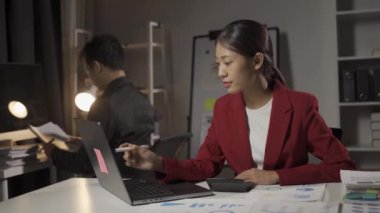 Genç Asyalı işadamı, kadın ve erkek dizüstü bilgisayarlar ve finansal belgelerle birlikte çalışıyor..