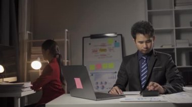 Genç Asyalı işadamı, kadın ve erkek dizüstü bilgisayarlar ve finansal belgelerle birlikte çalışıyor..