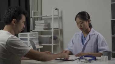 Erkek hasta, klinikte sağlık ve tıbbı tartışan Asyalı kadın doktoru ziyaret ediyor..