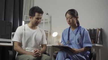 Erkek hasta, klinikte sağlık ve tıbbı tartışan Asyalı kadın doktoru ziyaret ediyor..
