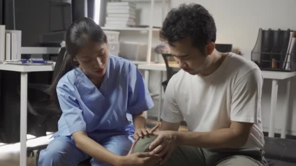 女性医師は男性患者に腕や脚の筋肉痛で身体療法をするように頼んだ 女性の医師は男性の卵の世話をするのを助けました — ストック動画