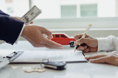 Araba satıcıları faiz oranlarını ve araba kredisini hesap makinesiyle hesaplarlar. Uzak fotoğraf ofisindeki şartlar ve koşullar hakkında müşterilere ayrıntılı olarak açıkla.