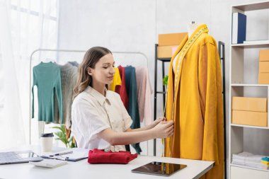 Moda blogcusu konsepti Canlı video, sosyal medya, dijital kamera ile çevrimiçi satış yapmak için kıyafetleri elinde tutan genç kadın..