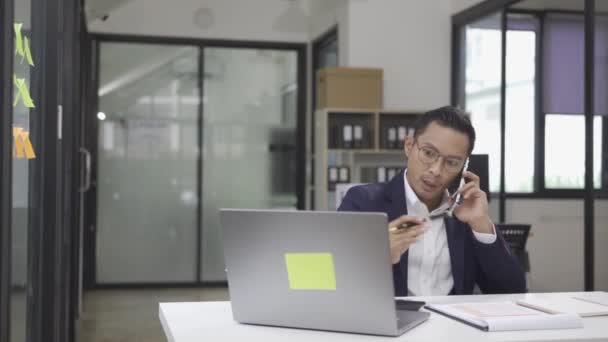 デスクで働く笑顔のアジアの男性会計士は オフィスの机に座っている計算機の執行マネージャーを使用して年次財務書類税を計算し 会社の財務会計書類を調べます — ストック動画