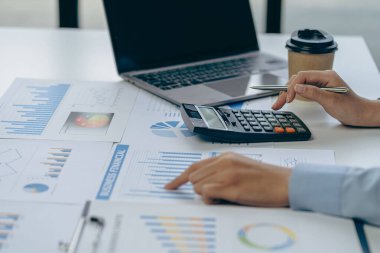 Çizelgeleri, grafikleri, bilgisayarı, yatırım tabletini inceleyen ve belgenin üstündeki hesap makinesine basan kadın muhasebeci. Muhasebeciler, muhasebeciler, memurlar, banka danışmanları ve denetçiler. yakın plan fotoğraf