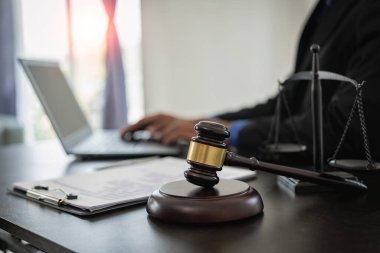 Mahkeme salonunda yasal sözleşme belgeleriyle çalışan orta yaşlı bir erkek avukat. Masada siyah teraziler, hukuk yargıcı danışmanlığı ve hukuk hizmetleri kavramı var.