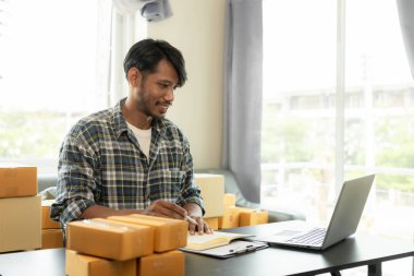 KOBİ işine başlıyorum. Bilgisayarda çalışan bir adam online siparişe ve paket kutusuyla online alışveriş ve teslimat konseptine bakıyor..