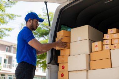 Genç siyah erkek kurye, teknoloji, takip ve kurye hizmeti konseptiyle mutlu teslimat yapıyor. Elinde karton kutularla dolu bir kamyon iş bölgesindeki bir adama bir paket teslim ediyor..