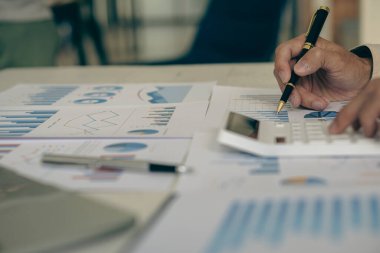 Yatırım grafiğini analiz eden ve belgeleri hesaplamak için hesap makinesi tuşuna basan işadamı dijital tablet üzerindeki mali belgelerin resmini kapatıyor