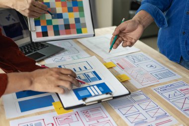 Web tasarımcılarından oluşan bir ekip, UI / UX ön uç tasarım kavramlarına sahip mobil yanıt veren bir web sitesi geliştirmek için birlikte çalışıyor. UxUi müteahhitlerinden oluşan bir ekip ahşap bir tezgahta birlikte çalışıyor..