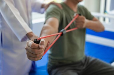 Doktorlar, fizyoterapistler kol ağrısı olan hastaları tedavi ediyor. Terapistini klinikte esneme hareketleri yaparken tedavi ediyorlar. Uzak Resim