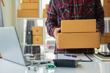 Genç adam internetten satış yapıyor ve KOBİ için çalışıyor. Genç Asyalı adam online siparişleri kontrol ediyor. Çevrimiçi Ticaret Fikirleri Uzaktan Satıyor. 