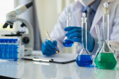 Bilim adamları, mikroskobik laboratuvarı olan bir laboratuvar şişesinde mavi ozon suyuyla bir şişe çivit çözeltisi üzerinde çalıştılar. Doktor Uzak Resim