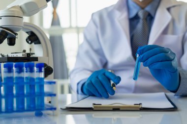 Bilim adamları, mikroskobik laboratuvarı olan bir laboratuvar şişesinde mavi ozon suyuyla bir şişe çivit çözeltisi üzerinde çalıştılar. Doktor Uzak Resim