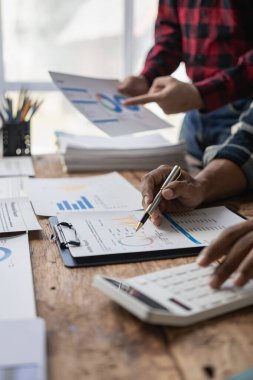 Genç işadamları beyin fırtınası yapıyor, mali istatistikleri birlikte tartışıyorlar, çok ırklı meslektaşlar yeni bir iş kurmak için ofis toplantılarında işbirliği yapıyorlar, takım çalışması kavramları. Uzak Resim