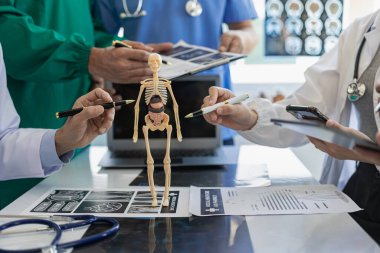 Beyaz laboratuvar önlüklü ve ameliyat önlüklü doktorlarla toplantılar, masalarda oturmak, tıbbi hasta kayıtlarını tartışmak, çeşitlilik gösterileri, işbirliği, veri analizi için takım çalışması veya atölyeler üzerinde çalışmak..