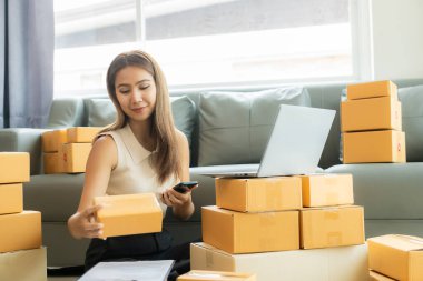 Küçük işletme girişimcisi, kurucu ya da serbest çalışan Asyalı bir kadın, paket kutuları ve dizüstü bilgisayarlarla çalışan başarılı bir Asyalı kadın, paketleme kutularıyla, çevrimiçi pazarlaması ve taşımacılığıyla.