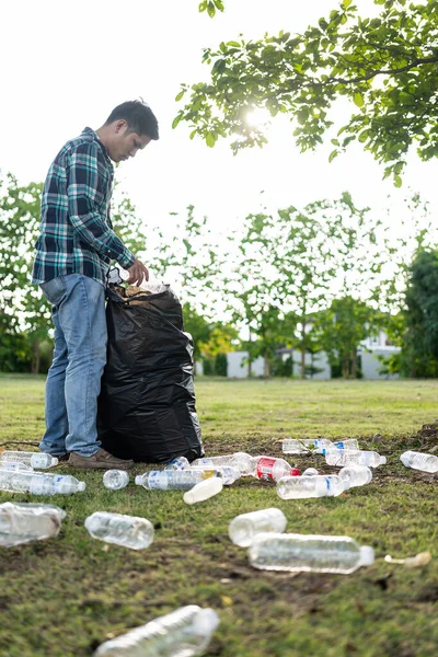 Adamın elleri çöp topluyor, boş plastik su şişeleri, yerde yahni, kuru yapraklar, çöp torbalarında plastik şişeler, temizlik, toprak ekoloji günü konsepti...