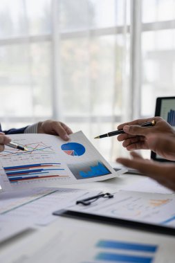 Şirket toplantısı sırasında dizüstü bilgisayar ve grafik belgesinde iş mali raporunun analiz edilmesi başarılı takım çalışmalarını dikey yakın plan görüntüsünü gösterir