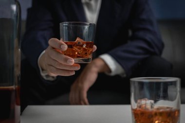 Alkol bağımlılığı ve insanların fikirleri. Evde viski içip içki içen alkolik bir adam. Lüks takım elbiseli bir işadamı.