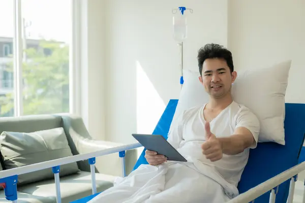 Young Asian man, patient lying on hospital bed, undergoing treatment in medical clinic. Health insurance or hospitality concept
