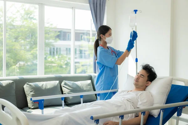 亚洲男病人躺在床上 医生在检查和询问病情 女护士在概念医院 医疗保险和医院服务部门填写健康清单 — 图库照片