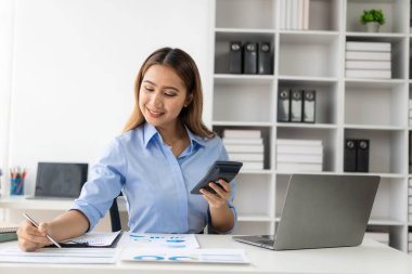 Evdeki mali belgeleri kontrol eden Asyalı kadın muhasebeci, çevrimiçi vergi makbuzunu ödemeden önce hesap makinesini kullanmalıdır. İş bütçesi planlaması 