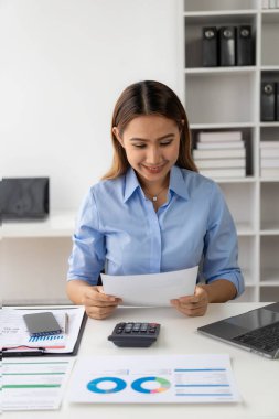 Evdeki mali belgeleri kontrol eden Asyalı kadın muhasebeci, çevrimiçi vergi makbuzunu ödemeden önce hesap makinesini kullanmalıdır. İş bütçesi planlaması dikey tablo