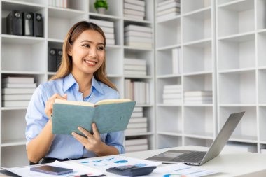 Evdeki mali belgeleri kontrol eden Asyalı kadın muhasebeci, çevrimiçi vergi makbuzunu ödemeden önce hesap makinesini kullanmalıdır. İş bütçesi planlaması 
