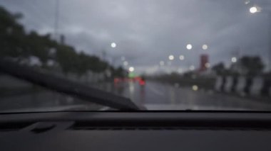 Yağmurlu bir günde, güzel ışıklar ve bokeh ile gece sokaklarda dolaşan bir arabanın içinden çekilmiş bir video..