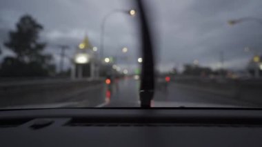 Yağmurlu bir günde, güzel ışıklar ve bokeh ile gece sokaklarda dolaşan bir arabanın içinden çekilmiş bir video..