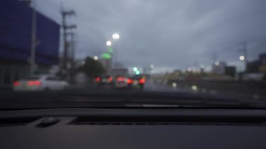 Yağmurlu bir günde, güzel ışıklar ve bokeh ile gece sokaklarda dolaşan bir arabanın içinden çekilmiş bir video..