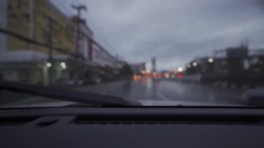Yağmurlu bir günde, güzel ışıklar ve bokeh ile gece sokaklarda dolaşan bir arabanın içinden çekilmiş bir video..