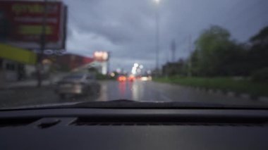 Yağmurlu bir günde, güzel ışıklar ve bokeh ile gece sokaklarda dolaşan bir arabanın içinden çekilmiş bir video..